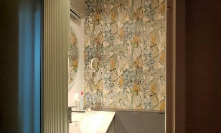 Après déplacement meuble vasque et pose papier peint jungle en face de la porte pour cette salle de bain à Lyon.